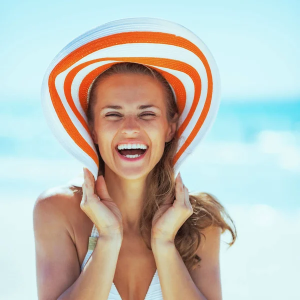 在海滩上戴着帽子微笑的年轻女子 — 图库照片