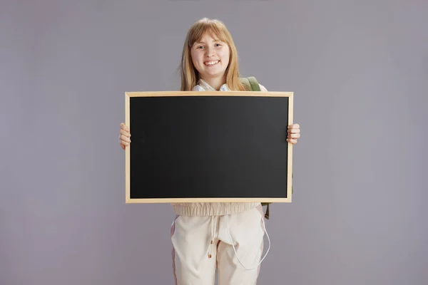 笑顔現代のティーン女の子でベージュトラックスーツショーブランクボードに対してグレー — ストック写真