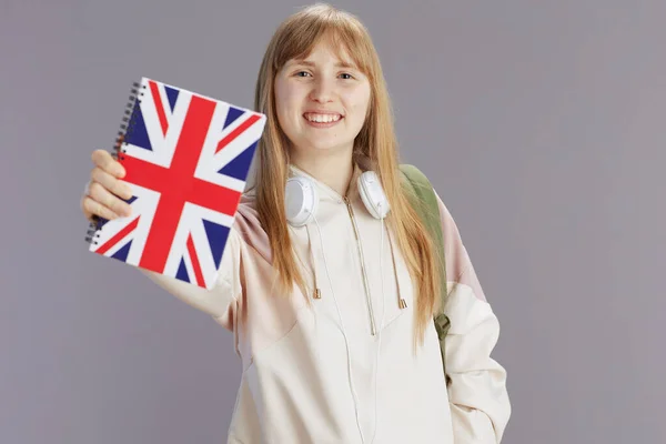 穿着米色运动服 戴着英国国旗工作手册 头戴灰色耳机的快乐时髦的少女 — 图库照片