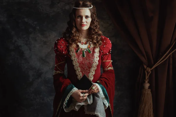中世纪的女王 穿着红色衣服 书和手帕 背景是深灰色的 — 图库照片
