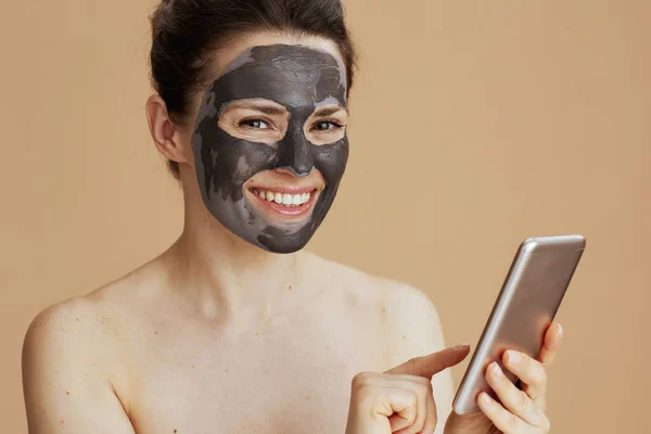 Portrait Happy Young Woman Smartphone Facial Mask Isolated Beige Background — Stock Photo, Image