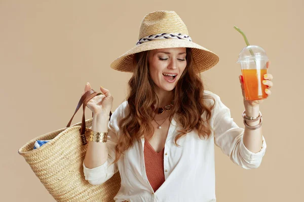 海滩度假 快乐优雅的40岁家庭主妇 身穿白衬衫 穿着米色背景短裤 头戴草袋 胡萝卜软糖和夏帽 — 图库照片