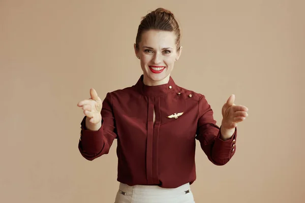 Glimlachende Stijlvolle Vrouwelijke Stewardess Geïsoleerd Beige Achtergrond Tonen Waar Uitgangen — Stockfoto