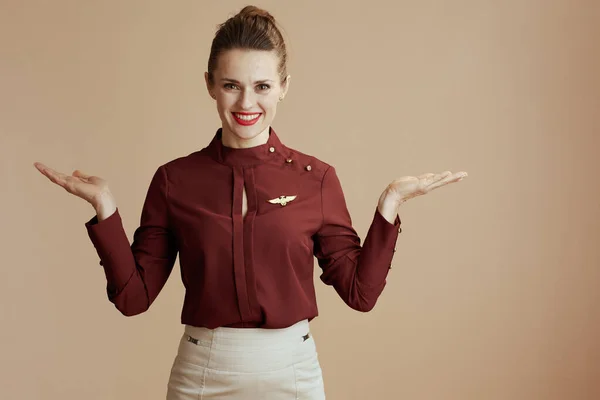Smiling Elegant Female Stewardess Presenting Something Empty Palm Beige Background — Stock Photo, Image