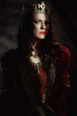 Koyu gri arka planda taçlı kırmızı elbiseli ortaçağ kraliçesi..