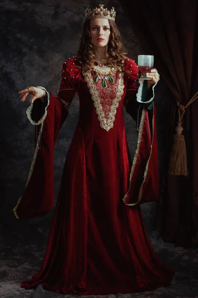 中古时代女王的全长画像 身穿红色衣服 戴着高脚杯 头戴深灰色背景的皇冠 — 图库照片