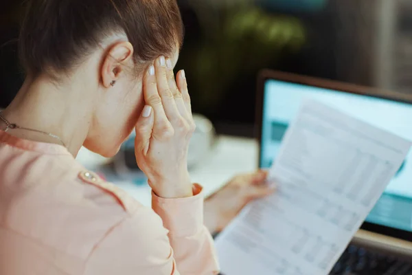 近代的なオフィスで頭痛を持っている文書を持つ現代のビジネス女性の後ろから見た — ストック写真