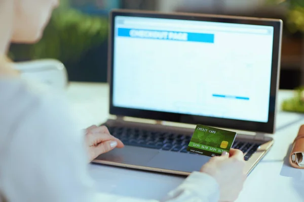 現代のオフィスで電子商取引のウェブサイト上でオンライン購入を行うラップトップとクレジットカードを持つ現代のビジネス女性の後ろから見た — ストック写真
