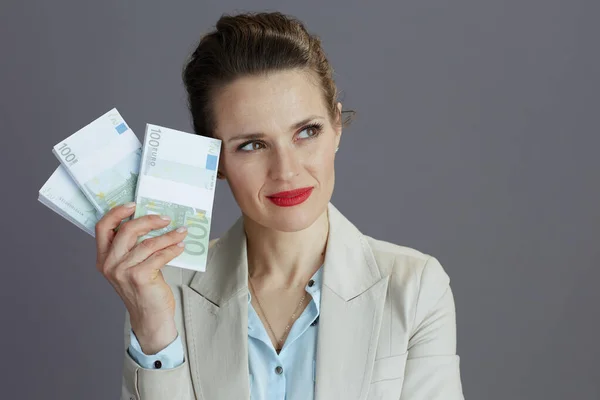 Tenksom Trendy Kvinne Liten Forretningsdress Med Euro Pengepakker Isolert Grått – stockfoto