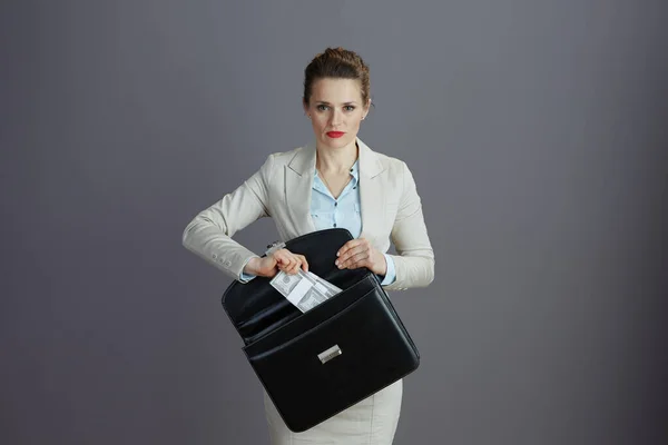 时尚的40岁的小企业主女人 身穿浅色西装 头戴公文包 头戴灰色背景的钞票包 — 图库照片