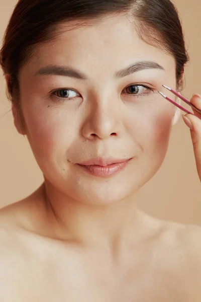 Porträtt Ung Asiatisk Kvinna Med Pincett Mot Beige Bakgrund — Stockfoto