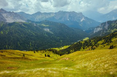 Dolomitlerde yaz zamanı. Dağlı, tepeli, bulutlu, otlu ve ormanlı manzara.