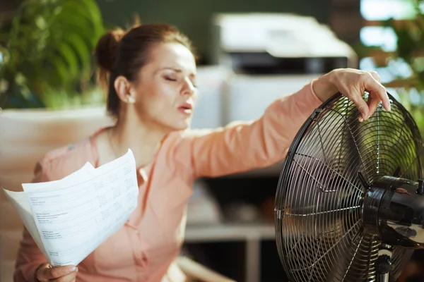 可持续工作场所 现代绿色办公室的现代女性员工 文件和电扇都饱受夏季炎热之苦 — 图库照片