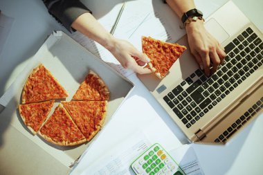 Sürdürülebilir iş yeri. Yeşil ofisteki pizza ve dizüstü bilgisayarlı iş kadını manzarası..