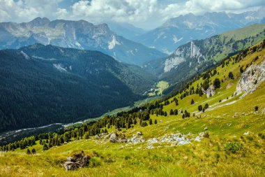 Dolomitlerde yaz zamanı. Dağlı, tepeli, bulutlu ve ağaçlı manzara.