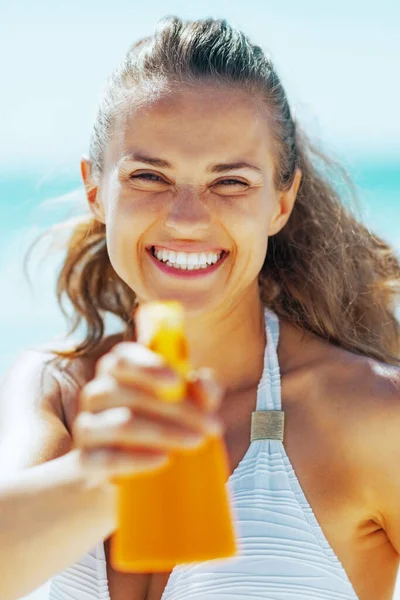 日焼け止めクリームの若い女性ポインティング ボトルをカメラで笑顔 — ストック写真