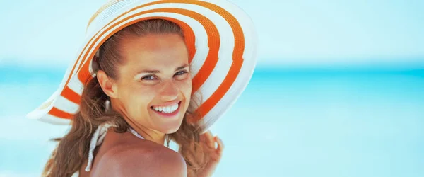 在海滩上戴着帽子微笑的年轻女子 — 图库照片