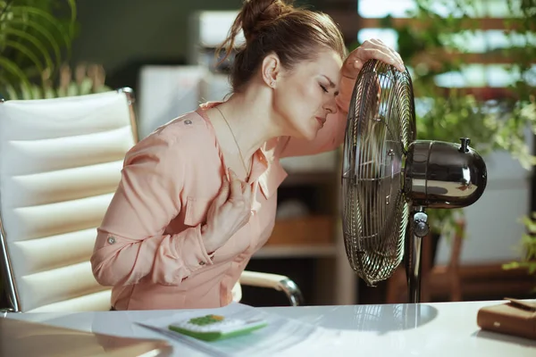 持続可能な職場 夏の暑さに苦しむ電動ファンと仕事をしている40歳の女性労働者 — ストック写真
