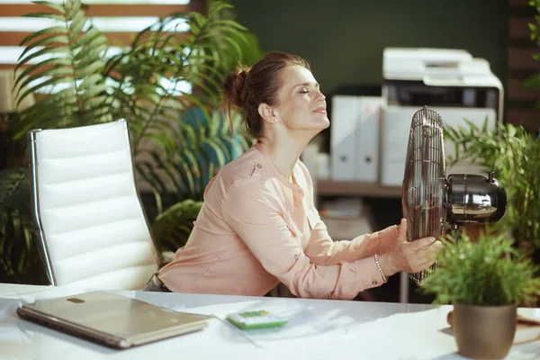 持続可能な職場 現代グリーンオフィスの幸せな現代女性従業員と電気ファン — ストック写真