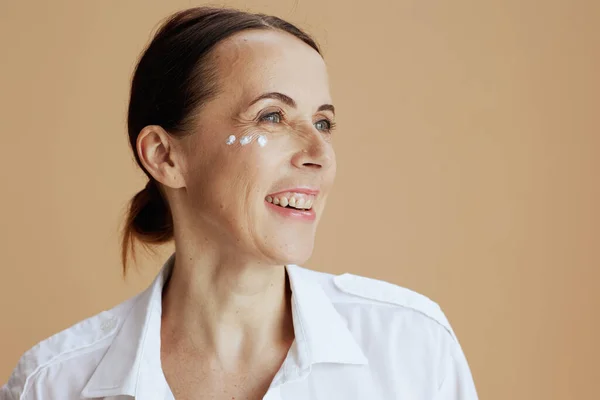 Šťastná Moderní Žena Oční Krém Obličeji Bílé Košili Izolované Béžovém — Stock fotografie