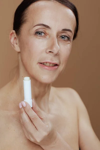 Moderne Jährige Frau Mit Hygienischem Lippenstift Auf Beigem Hintergrund — Stockfoto