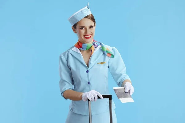 Uśmiechnięta Stylowa Stewardessa Niebieskim Tle Niebieskim Mundurze Torbą Kółkach Biletem — Zdjęcie stockowe