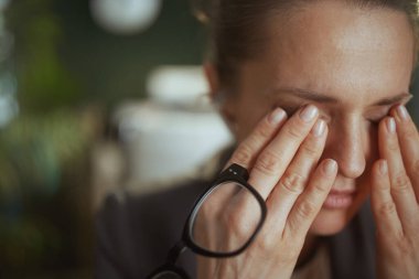 Sürdürülebilir iş yeri. Modern yeşil ofiste gözlüklü, yorgun, küçük işletme sahibi bir kadın..