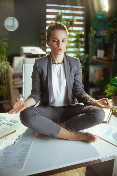 Sustainable workplace. relaxed modern business woman in modern green office meditating.