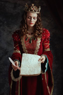 Kırmızı elbiseli ortaçağ kraliçesi. Parşömen ve tacı koyu gri arka planda..