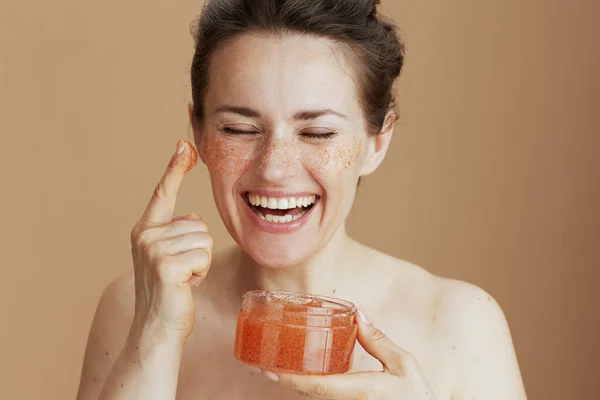 Šťastná Moderní Žena Obličejem Drhnutí Béžovém Pozadí — Stock fotografie