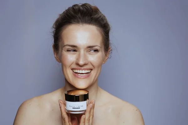Glimlachende Jonge Vrouw Met Cosmetische Crème Pot Blauwe Achtergrond — Stockfoto