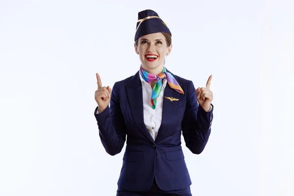 穿着制服的现代女空姐对着白色背景微笑 指着什么东西 — 图库照片