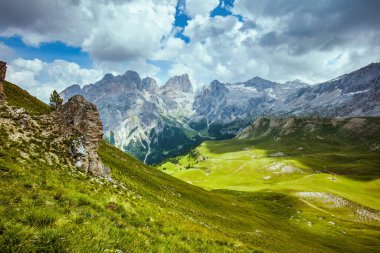 Dolomitlerde yaz zamanı. Dağlı, tepeli, bulutlu ve otlu manzara.