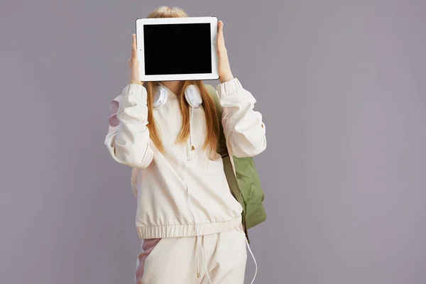 Modern Girl Beige Tracksuit Backpack Headphones Showing Tablet Blank Screen — Stock Photo, Image