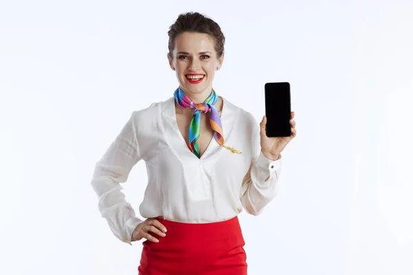 Usmívající Moderní Ženský Letuška Izolované Bílém Pozadí Uniformě Zobrazující Smartphone — Stock fotografie