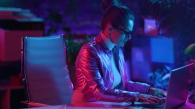 Neon metaverse futuristic concept. pensive trendy woman in glasses with laptop in modern office.