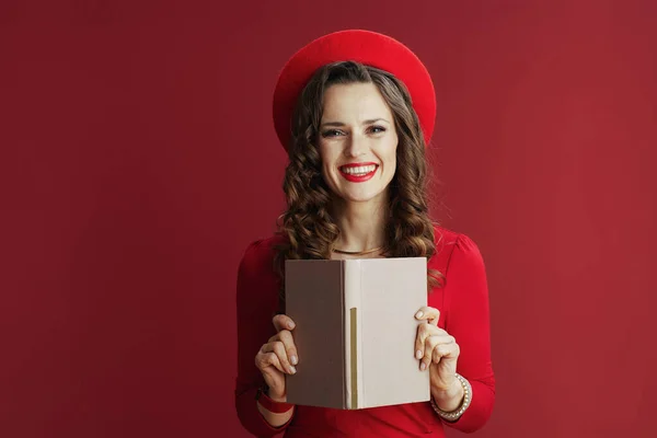 ハッピーバレンタイン 赤のドレスとベレー帽でスタイリッシュな中年女性の肖像画は本で赤の背景に隔離 — ストック写真