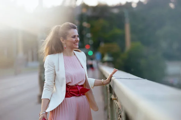 在城市的桥上 穿着粉色衣服和白色夹克的时尚女性 — 图库照片