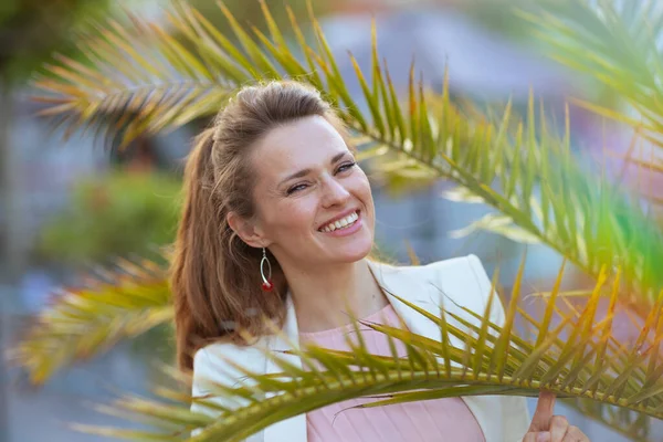 Şehirde Tropikal Ağacın Yanında Pembe Elbiseli Beyaz Ceketli Mutlu Zarif — Stok fotoğraf