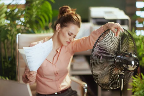 可持续工作场所 在现代绿色办公室工作的现代女工 文件和电扇都受到夏季炎热的折磨 — 图库照片