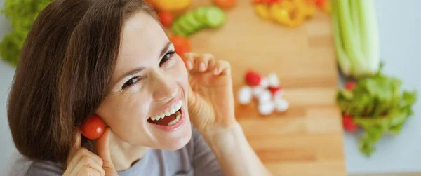 微笑的年轻女士使用樱桃西红柿作为耳环 — 图库照片