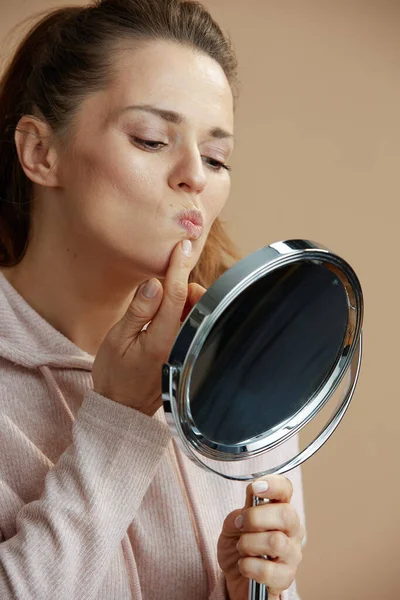 40岁妇女 嘴唇上有疱疹 米色背景上有镜子 — 图库照片
