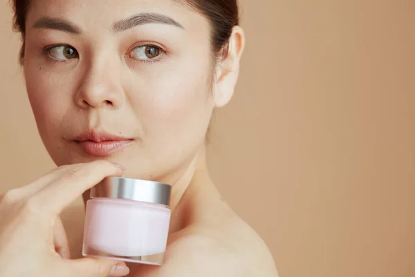 Jong Aziatisch Vrouw Met Gezichtscrème Pot Tegen Beige Achtergrond — Stockfoto