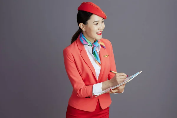 穿着红色短裙 夹克和帽子 背景为灰色的剪贴板的亚洲女人 — 图库照片