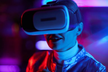 Neon metaevren fütüristik konsepti. Siyah arka planda vr kulaklıklı mutlu şık iş kadını.
