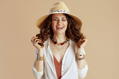 Plaj tatili Beyaz bluzlu ve şortlu mutlu ev hanımı bej arka planda yaz şapkalı..
