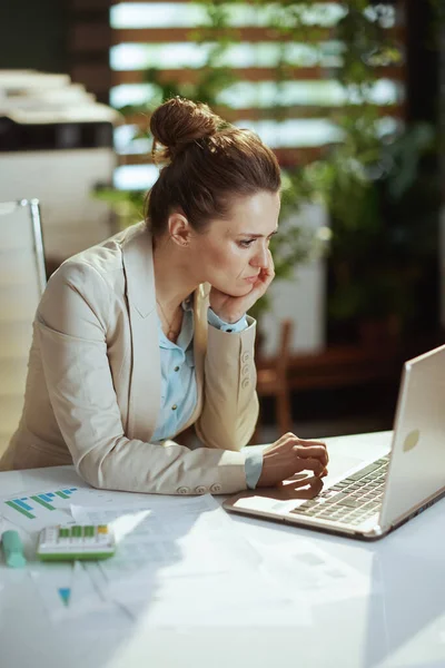 現代の40歳の女性社員ノートパソコン付きのモダンなグリーンオフィスで軽いビジネススーツを着て — ストック写真