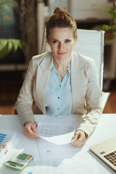 文書と現代の緑のオフィスで軽いビジネススーツの現代的な中年女性従業員の肖像 — ストック写真