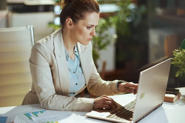 現代の中年会計士の女性ノートパソコン付きグリーンオフィスで軽いビジネススーツを着て — ストック写真