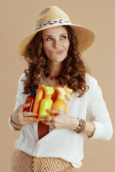 ビーチ休暇 白のブラウスと短パンの流行の女性は日焼け止めと麦藁帽子でベージュに隔離 — ストック写真